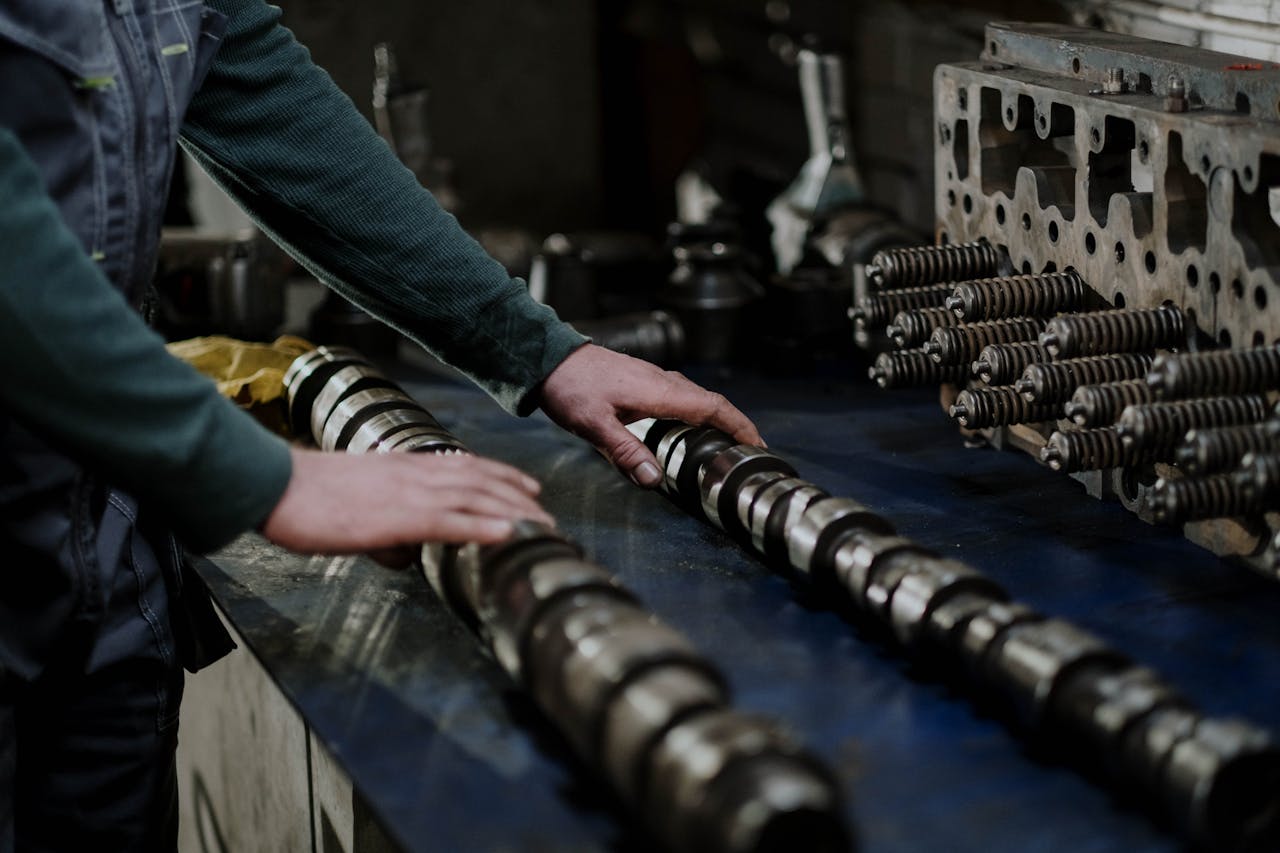 about-03 Worker handling camshafts and cylinder head in a mechanic workshop.
